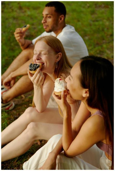 Three friends savor cupcakes in a serene outdoor s