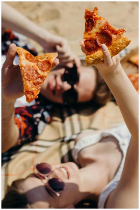 Two friends enjoying a sunny picnic with pepperoni
