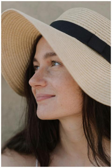 Portrait of a smiling woman wearing a sun hat, enj