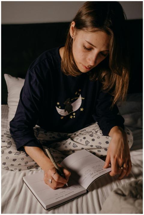 A young woman writing in a journal while sitting o