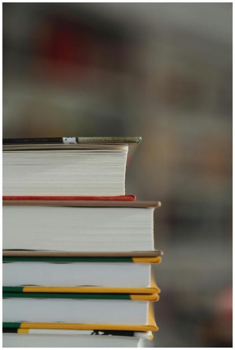 A vertical stack of hardcover books with a blurred