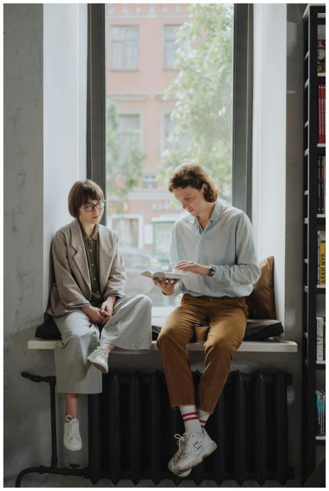 Two young adults enjoy a book in a cozy indoor set