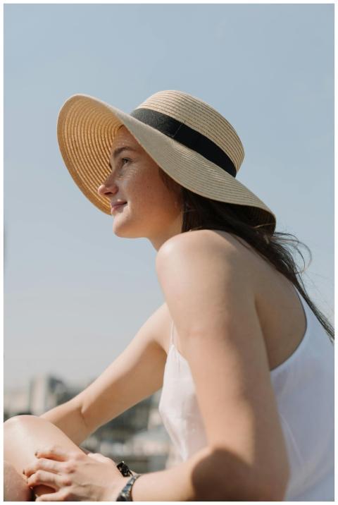 Charming woman in summer hat relaxing outdoors, en
