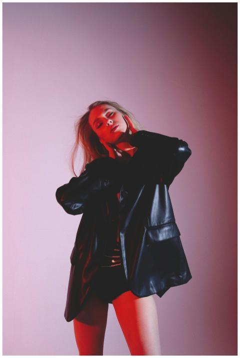 Young woman in a black leather jacket striking a c