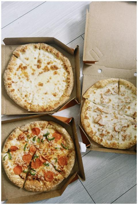 Top view of assorted pizzas in cardboard boxes on
