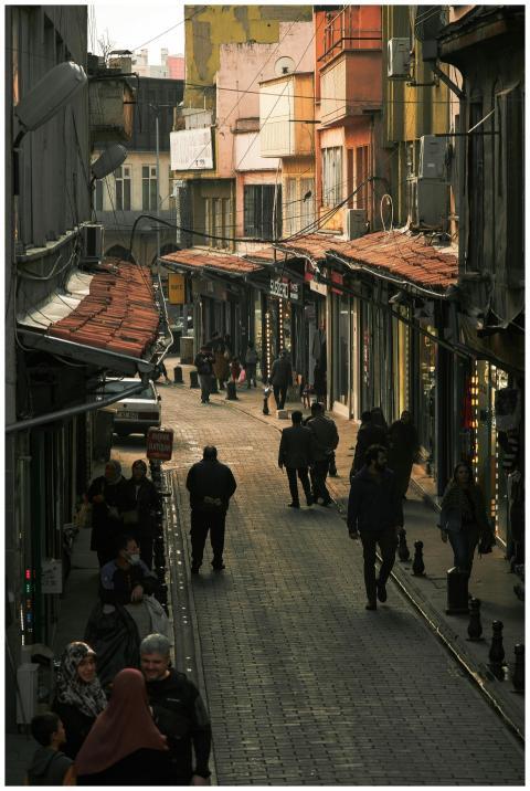 Crowd walking down a lively alleyway lined with sh