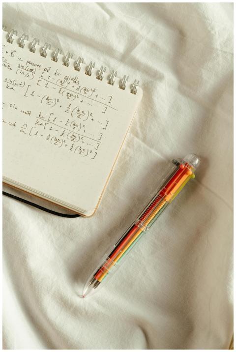 Handwritten math formulas on a notepad with a colo
