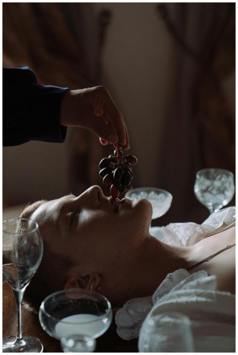 A dramatic scene of a man with grapes in luxurious