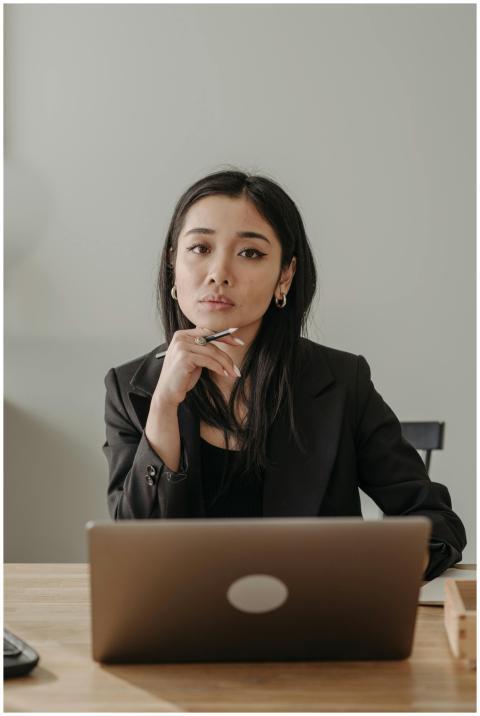 Asian woman in business attire working on a laptop