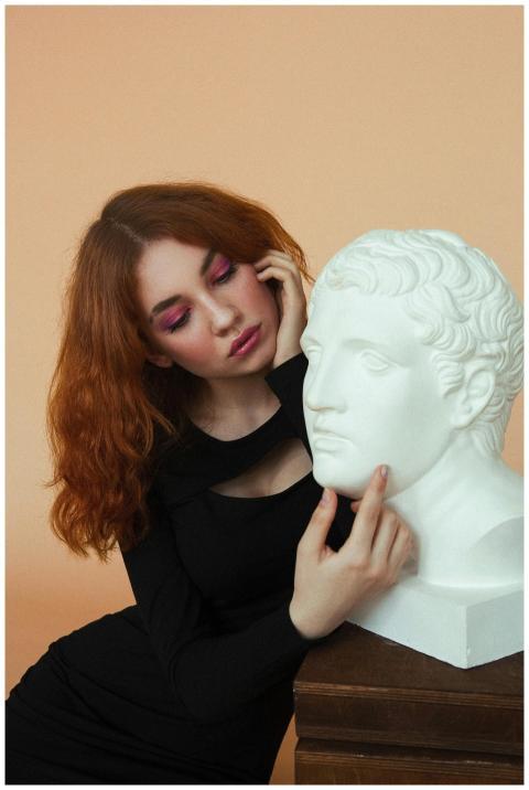 Thoughtful young female in black dress with makeup