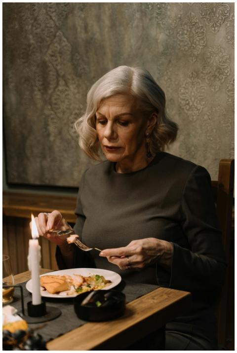 Senior woman with gray hair dining elegantly by ca