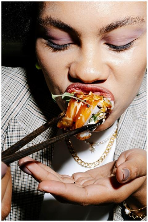 Close-up of a woman eating sushi with chopsticks,