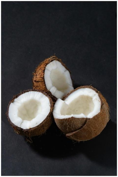 Three freshly opened coconuts displayed on a dark
