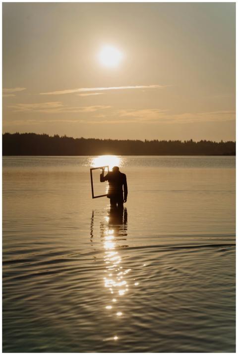 A silhouette of a person holding a frame in a calm