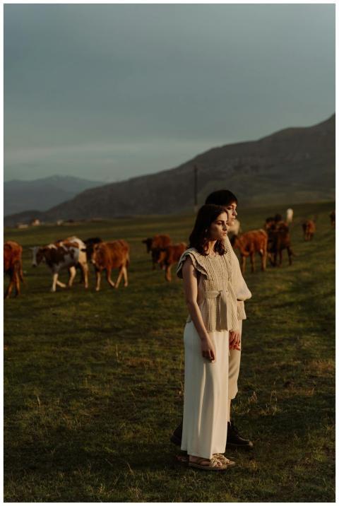 A tranquil scene of two people standing with cows