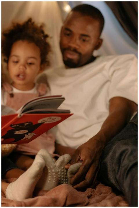 A loving father reads a storybook with his daughte