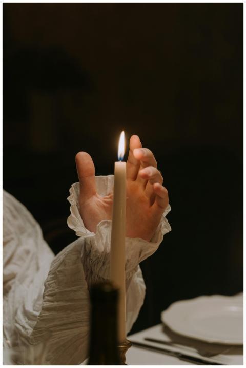 A serene candlelit scene featuring a hand gently h