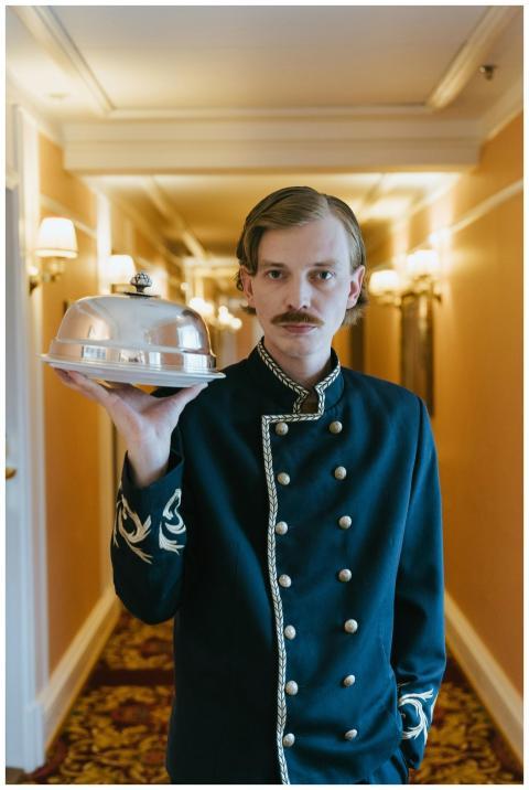 Hotel staff member in uniform presenting a serving
