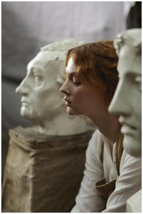Pensive woman sitting with classical sculptures, r
