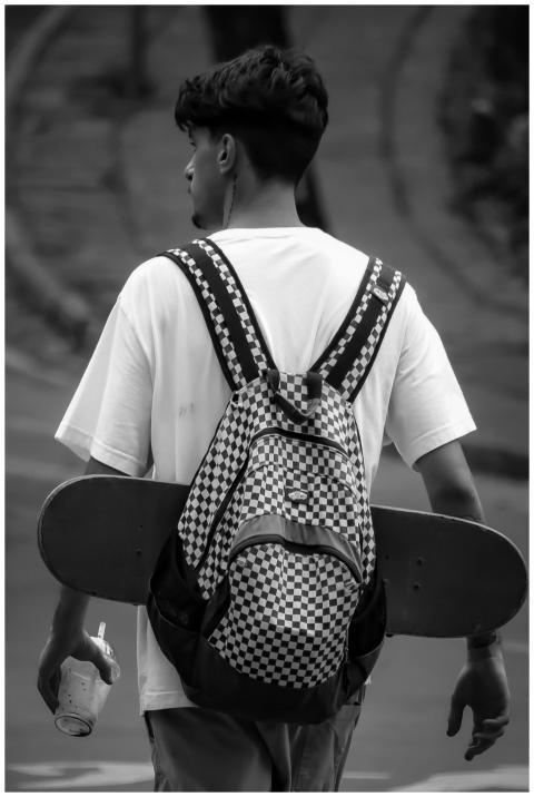 Young man in São Paulo carrying skateboard and bac
