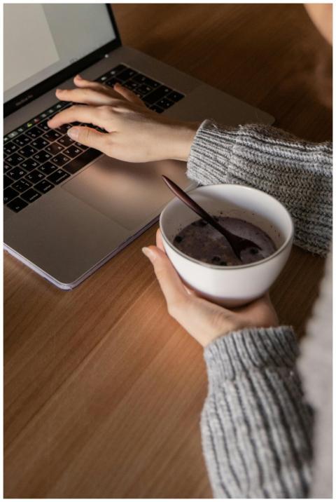 Person working on a laptop while holding a bowl of