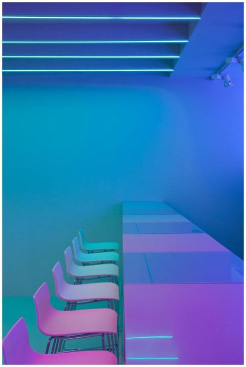 A modern interior with neon lighting, chairs, and