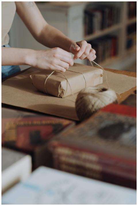 Hands visible wrapping a book with craft paper and