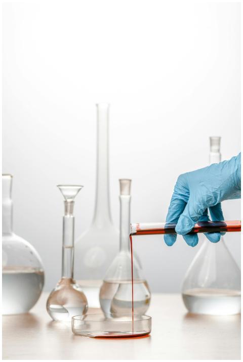 Close-up of a scientist pouring red liquid into a