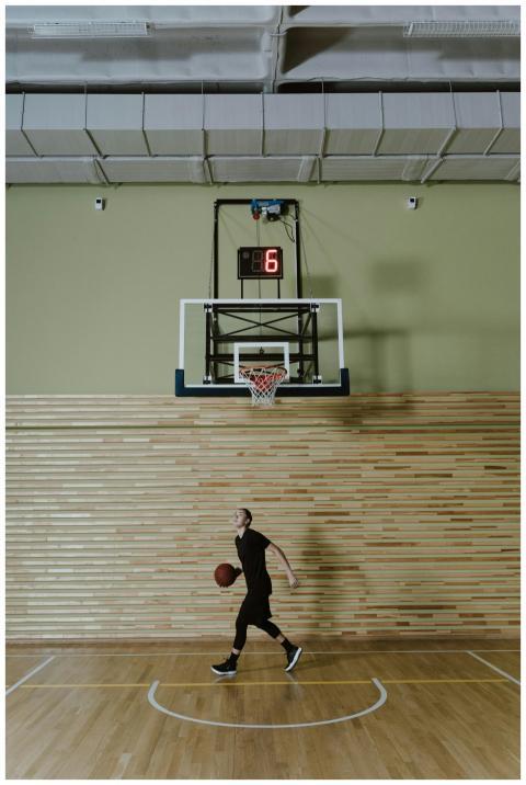A woman dribbling a basketball indoors beneath a s