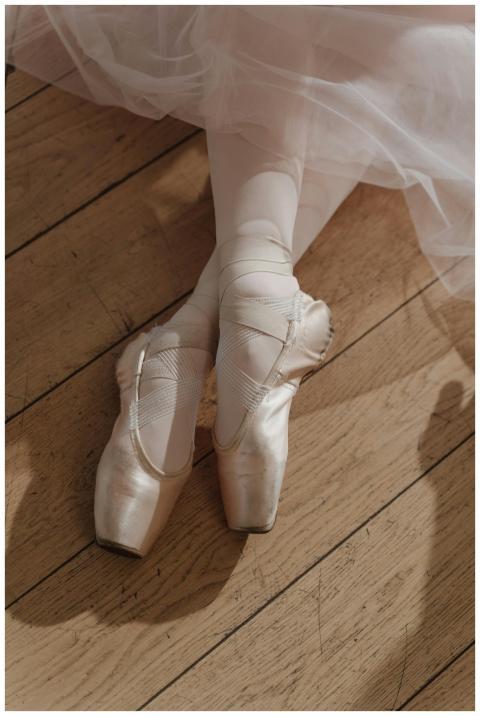 Close-up of pointe shoes and tutu on wooden floori