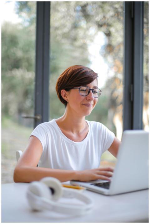 A happy woman with short hair using a laptop indoo