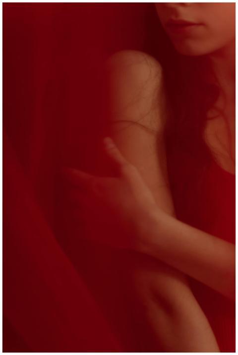 Artistic portrait of a woman in red, softly lit wi