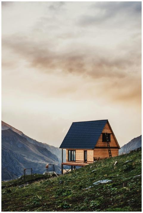 A serene wooden cabin sits on a hillside with a dr