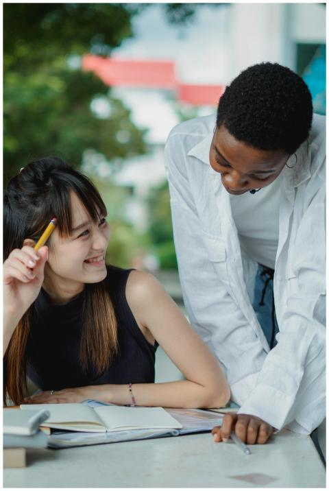 Two diverse students collaborate on a project outd