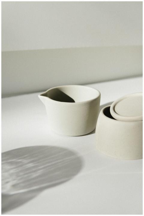 Elegant white porcelain cups with shadows on a bri