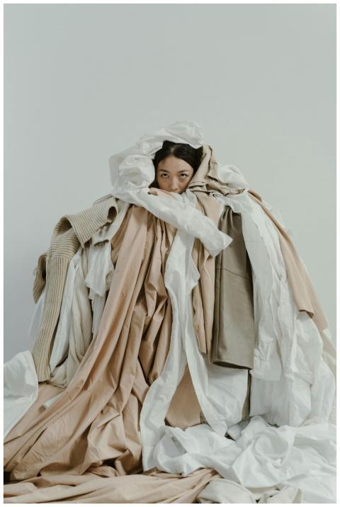 Asian woman partially hidden under layers of neutr