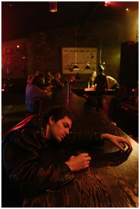 A man in a leather jacket appears sleepy at a diml