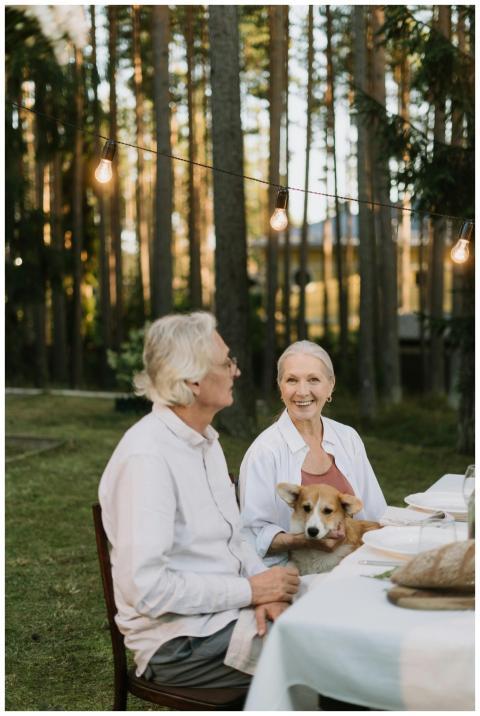 Elderly couple dining outdoors with a corgi, embra