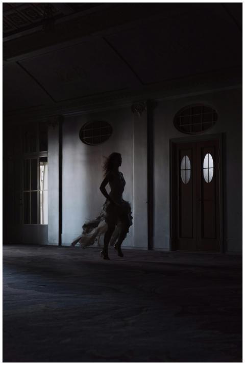 A silhouetted woman in a flowing wedding dress run