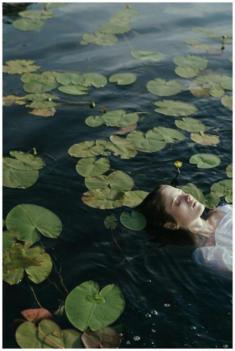 A woman peacefully floats in a pond surrounded by