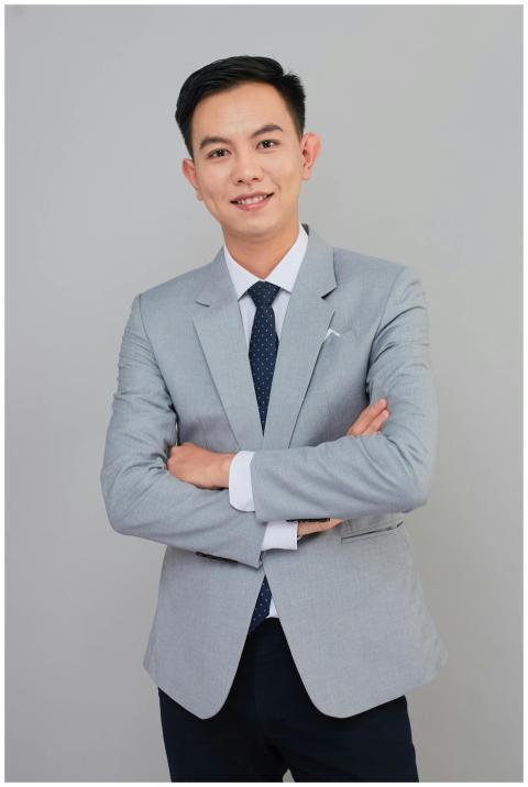 Smiling businessman in grey suit, arms crossed, pr