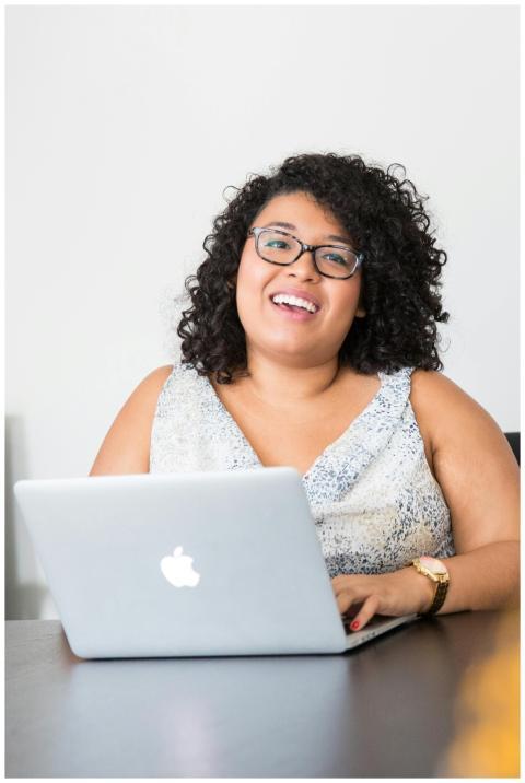 Happy businesswoman with curly hair using a laptop