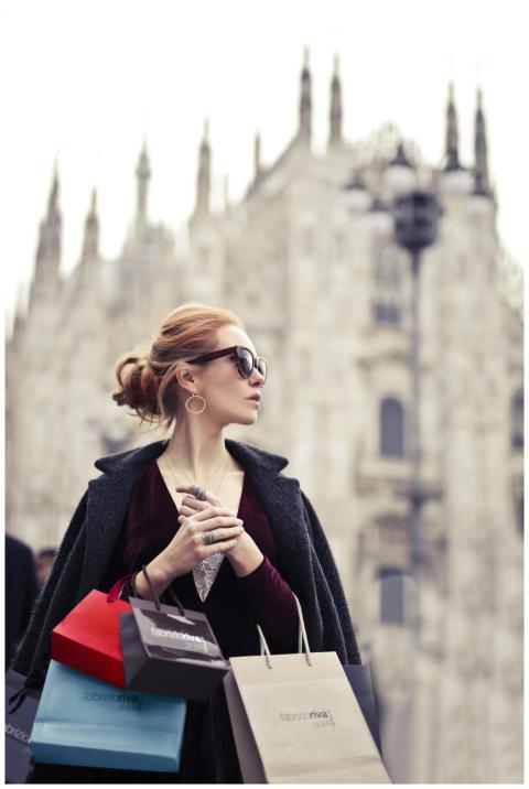 Fashionable woman holding shopping bags in front o