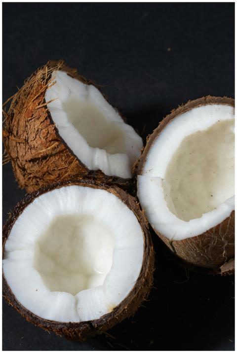 Close-up of three fresh coconut halves revealing w