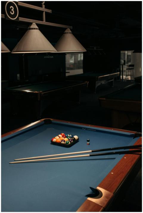 Dimly lit billiard room featuring a pool table wit
