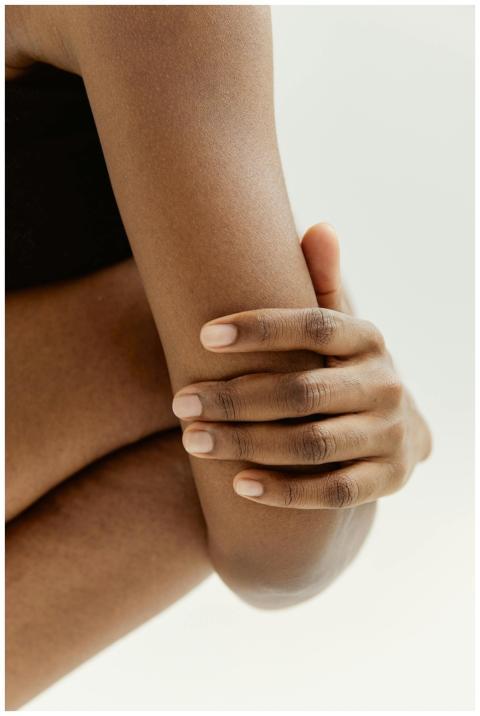 A close-up shot of a hand resting on an arm, captu