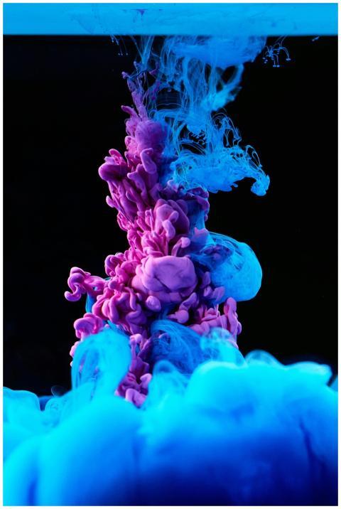 Vibrant blue and purple ink swirling in water crea