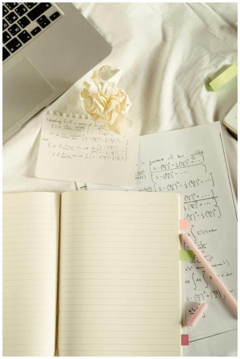 A flat lay image featuring a laptop, notebooks, an