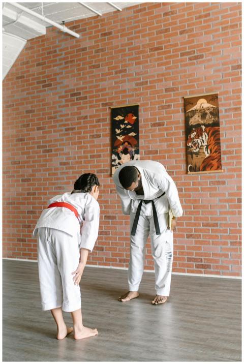 A sensei and a child in martial arts uniforms bowi