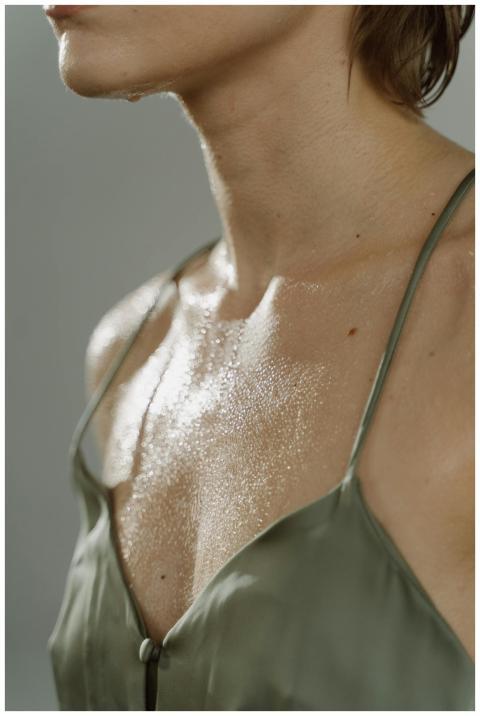 Close-up of a woman's wet chest in a green silk to